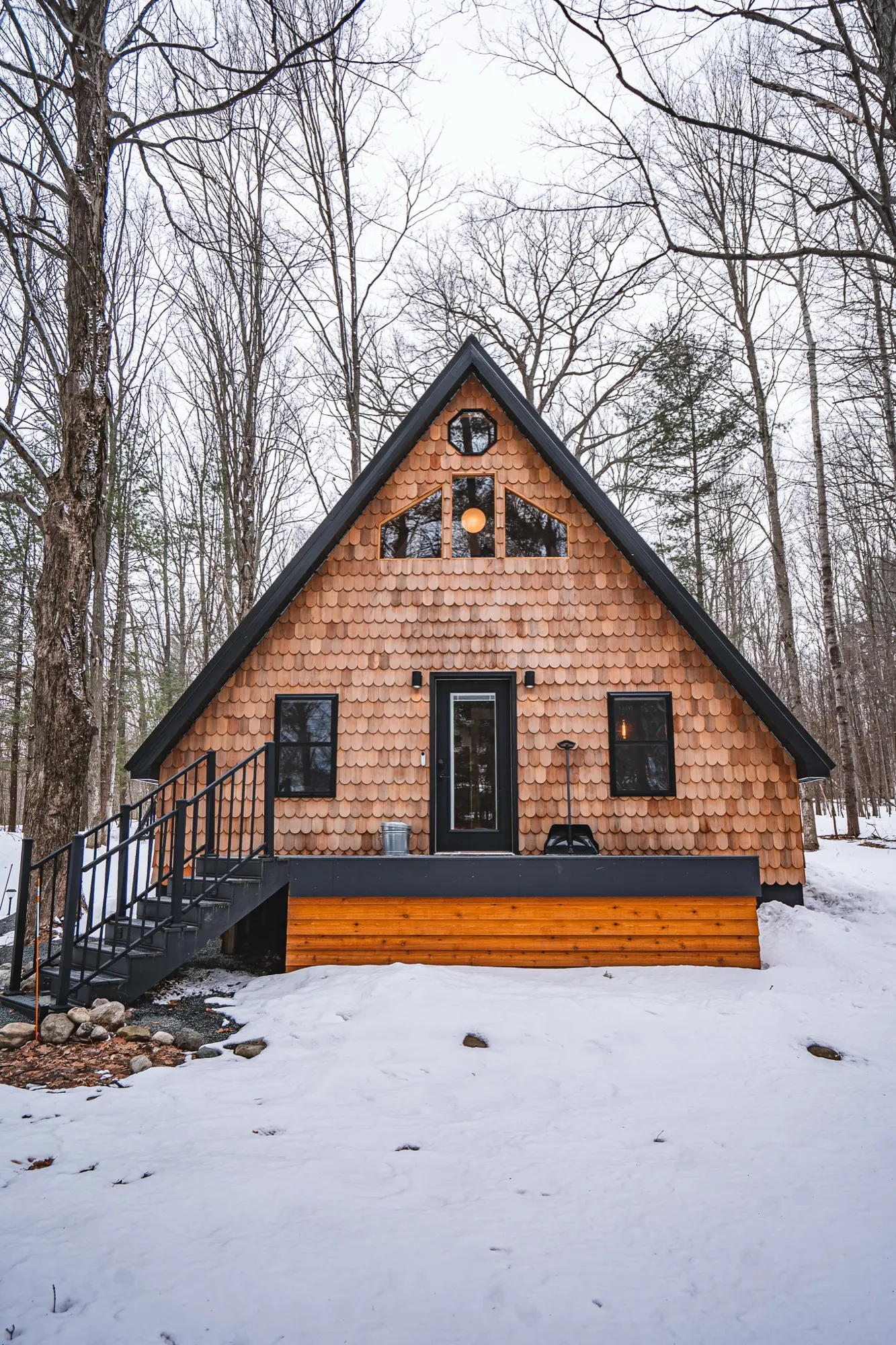The Roost A-Frame cabin in winter with fresh snow and warm glowing windows