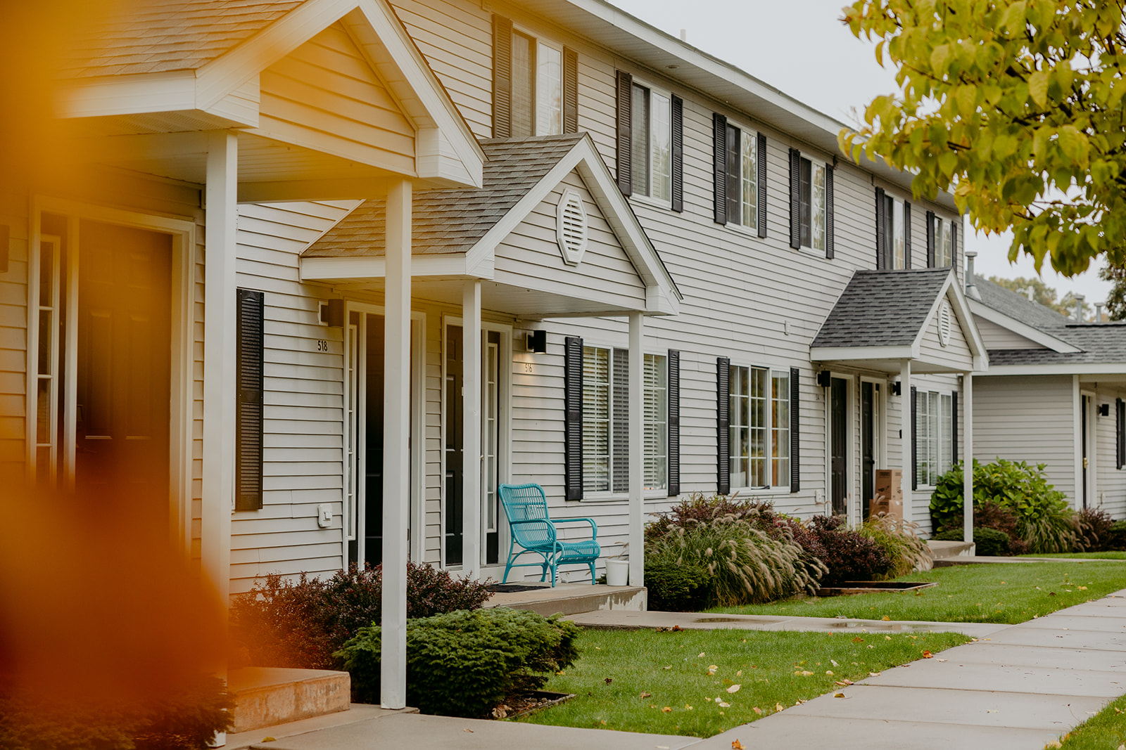 Row of white Roost North townhouses with covered porches on a quiet residential street in Traverse City