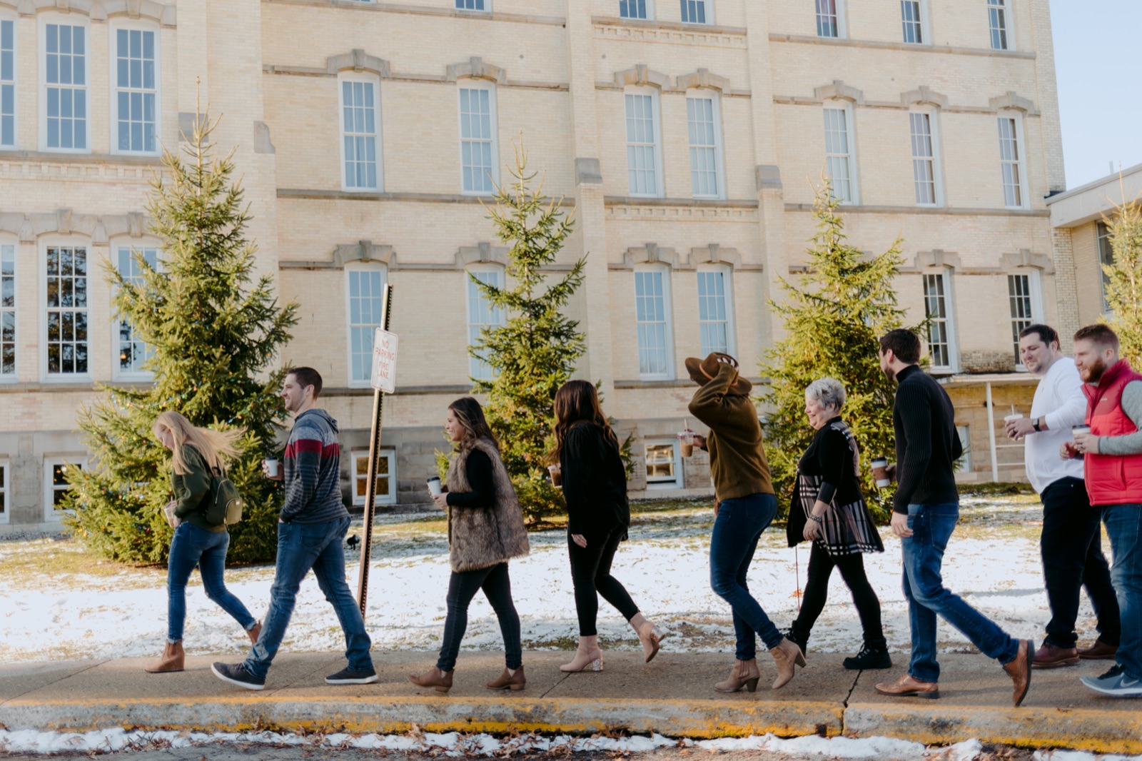 Friends walking past the historic Building 50 at the Grand Traverse Commons in Traverse City on a winter day with snow on the ground
