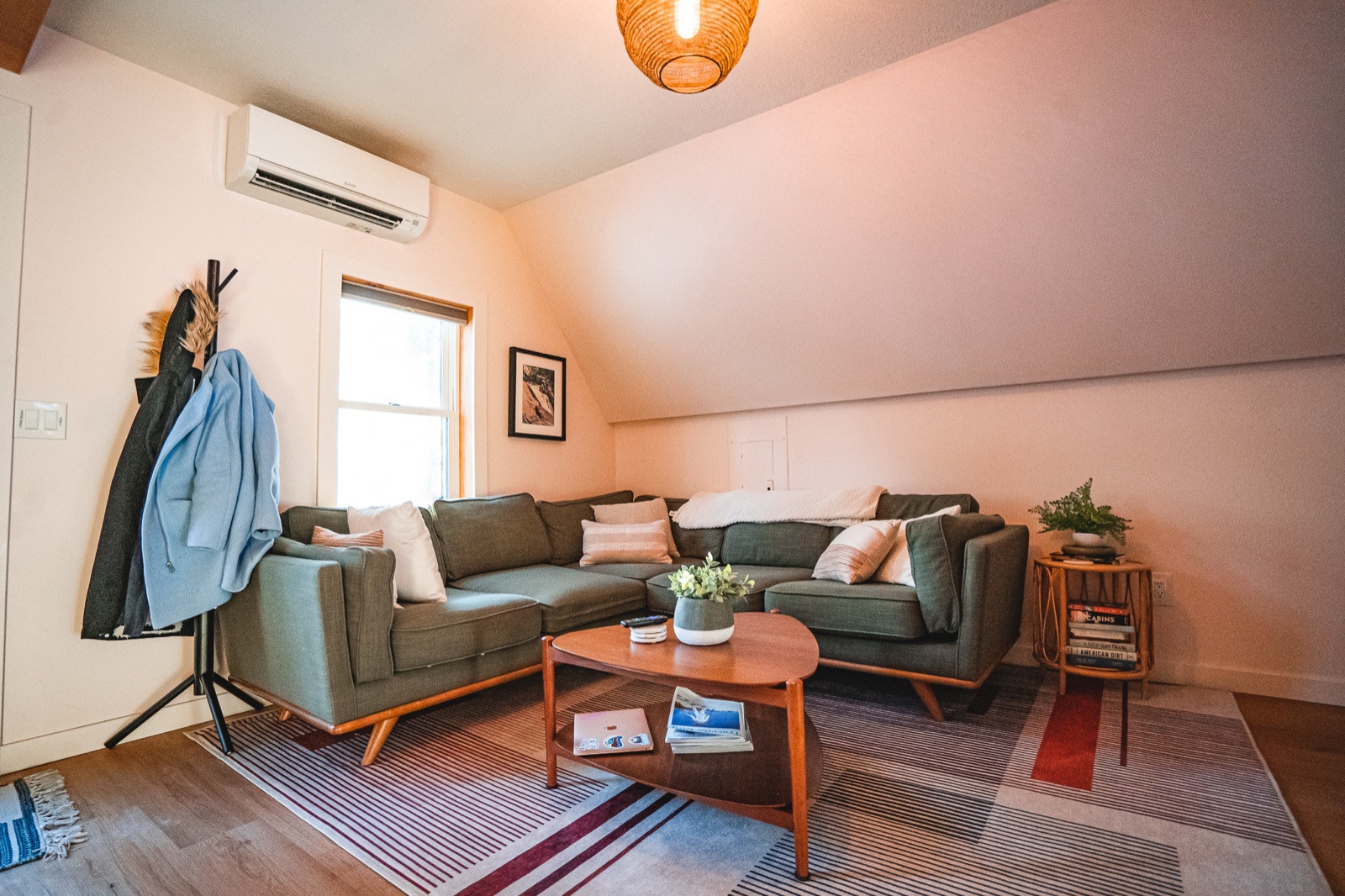 Living area inside the Roost A-Frame cabin with a green mid-century sectional sofa under the sloped ceiling