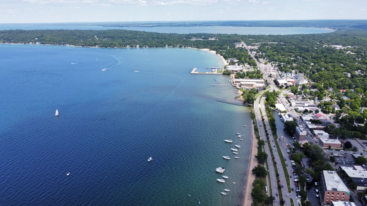 Aerial view of West Grand Traverse Bay with sandy beach, moored sailboats, and downtown Traverse City